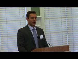 Man in suit standing at at lecture podium